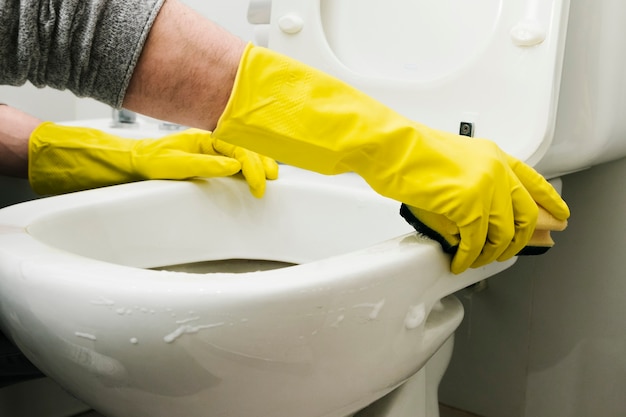 close up man cleaning toilet with sponge