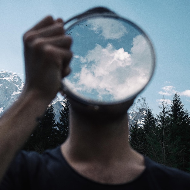 Photo close-up of man covering face with mirror