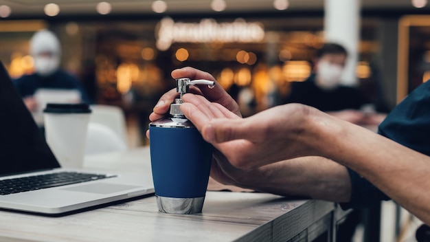 Close up a man disinfecting his hands sitting at a table in a\
cafe photo with a copyspace