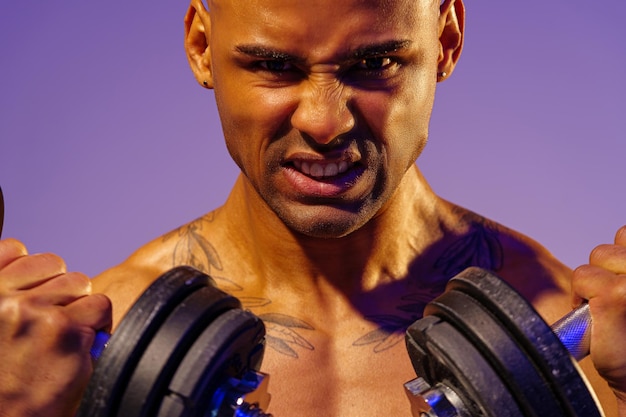 Close up of man doing exercise with weight dumbbells on studio background strength and motivation