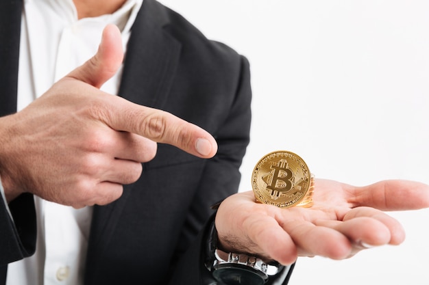 Close up of a man dressed in suit holding bitcoin