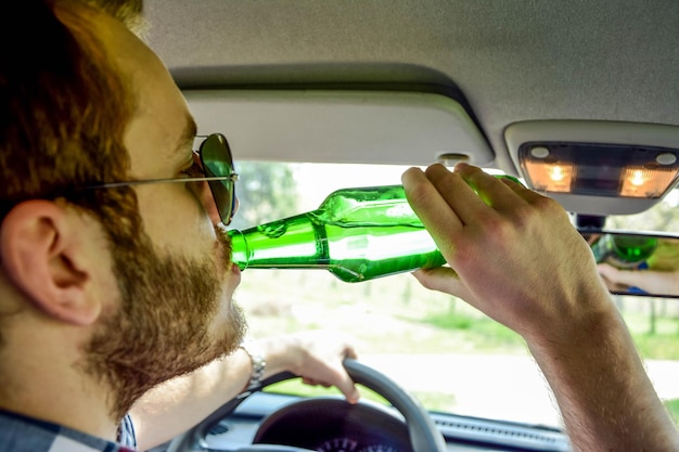 Foto close-up di un uomo che beve birra mentre guida un'auto