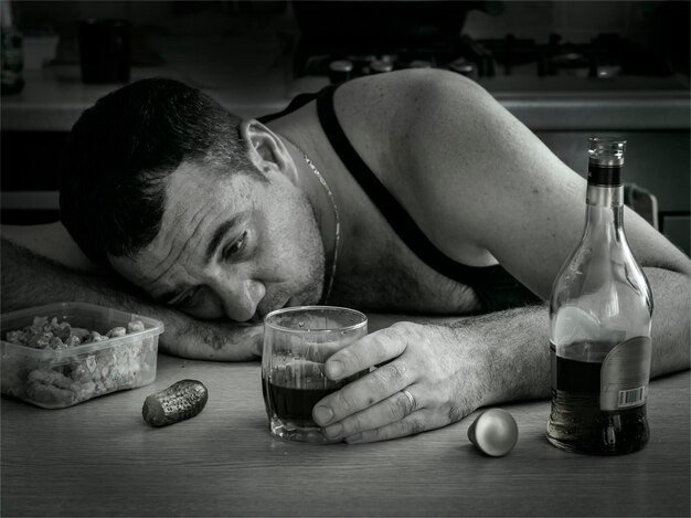 Foto close-up di un uomo che beve whisky sul tavolo