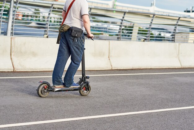 市内の電動スクーターで運転する男のクローズアップ