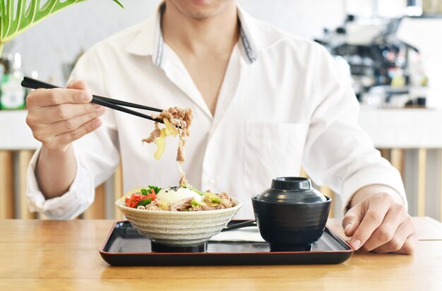 牛丼や日本食の牛丼を食べる男性をクローズアップ