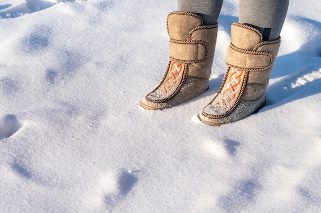 Close-up of a man in felt boots standing in the snow.