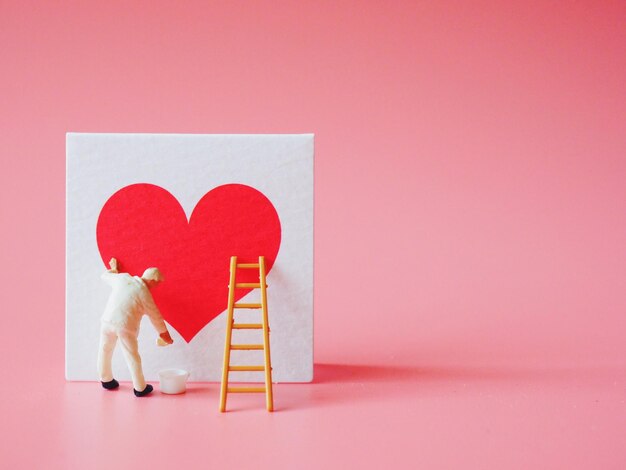 Photo close-up of man figurine with heart shape against colored background