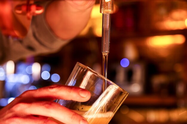 Foto close-up di un uomo che riempie un bicchiere di birra dal rubinetto di un bar