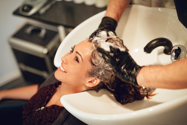 Close-up of a  man hairdresser washing the hair of a woman.