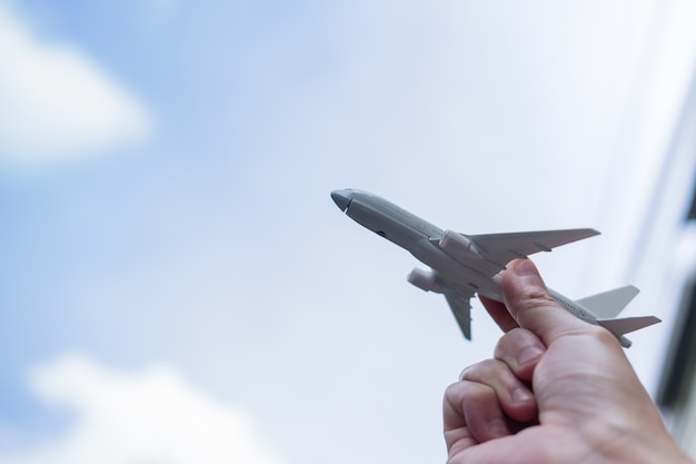 Chiuda in su della mano dell'uomo che tiene il giocattolo dell'aeroplano e alza fino al cielo