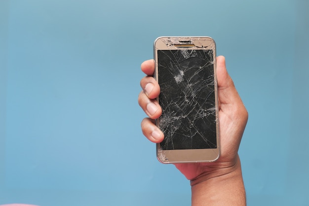 Close up of man hand holding broken smart phone.