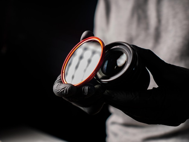 Photo close-up of man hand holding camera lens black background