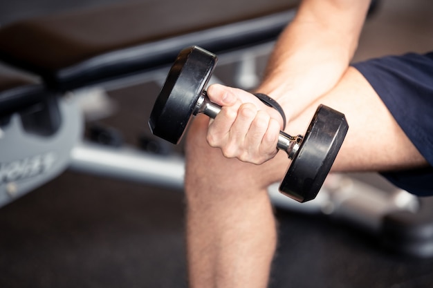 Close up of a man hand holding dumbbell at fitness gym