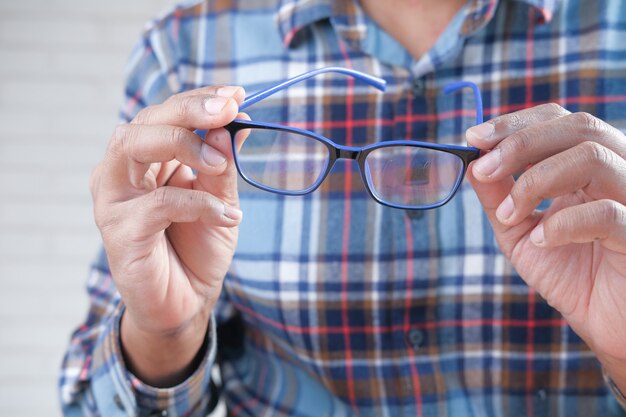 暗闇の中で眼鏡を持っている男の手のクローズアップ