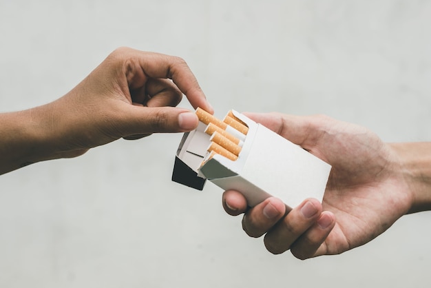 Close up man hand holding peel it off cigarette pack prepare
smoking a cigarette. packing line up. cigarette smoke spread.