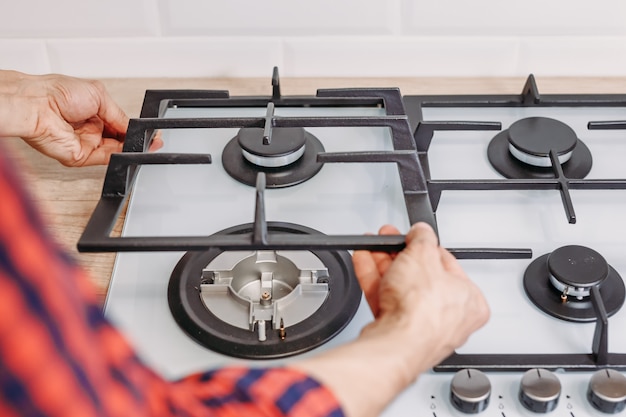 Close up of man hand install burner ongas hob in kithen. Repairs of gas control panel