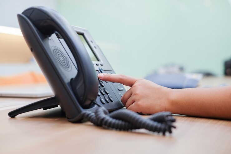 close up man hand pointing try to press button number on telephone office desk