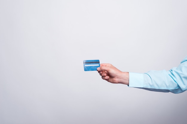 Закройте вверх по руке человека показывая синюю кредитную карту.