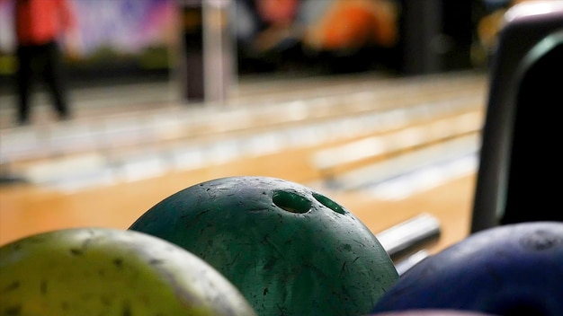 Foto primo piano per la mano dell'uomo che prende una palla da una rastrelliera e la lancia sulla pista da bowling media il giocatore