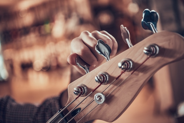 Close up man mano torsioni pioli sulla tastiera della chitarra