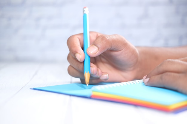 Photo close up of man hand writing on notepad