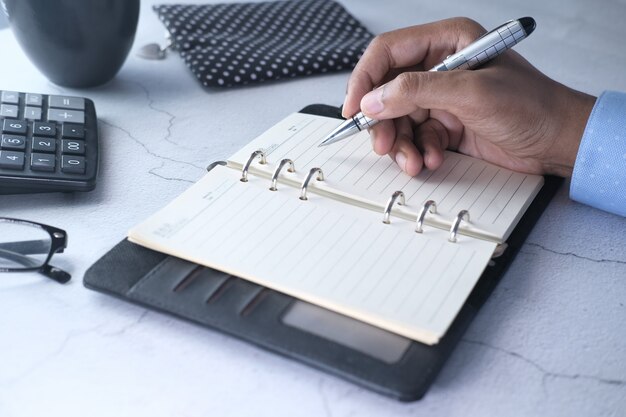 Close up of man hand writing on notepad.