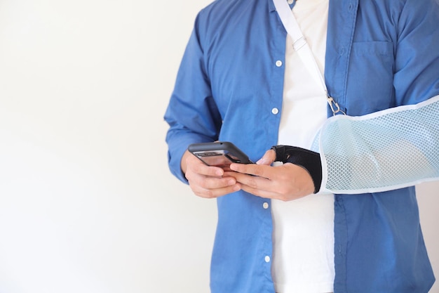 Close-up man handen dragen slinger op gebroken arm met behulp van slimme telefoon.