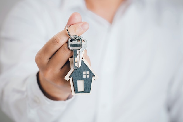 Close up man handing a house key .Concept of buying real estate