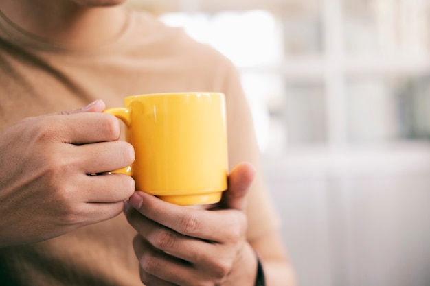 Chiuda sulle mani dell'uomo che tengono una tazza di caffè