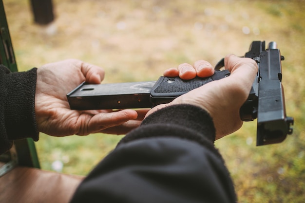 Close-up of a man hands holding and loading gun magazine in the pistol at the shooting range.