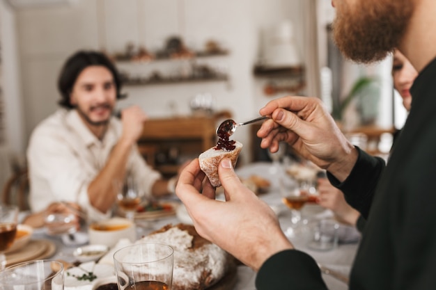 写真 カフェでパンと小さなスプーンのスライスを保持している男の手を閉じます