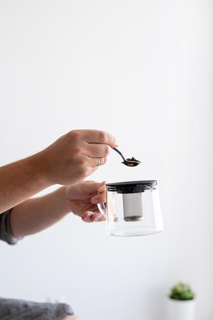 Photo close up of man hands pouring tea leaves into the teapot