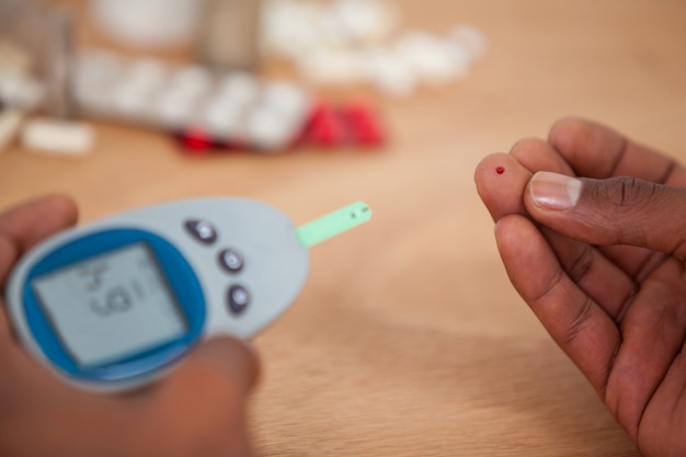 Close-up of man hands testing blood sugar with glucometer