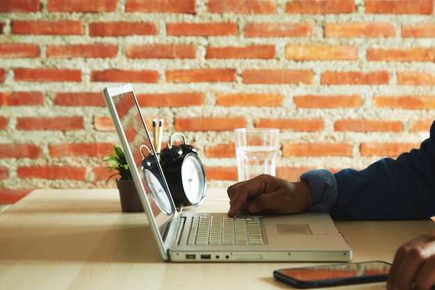 Close up of man hands typing on a laptop computer keyboard on the table with sunlight