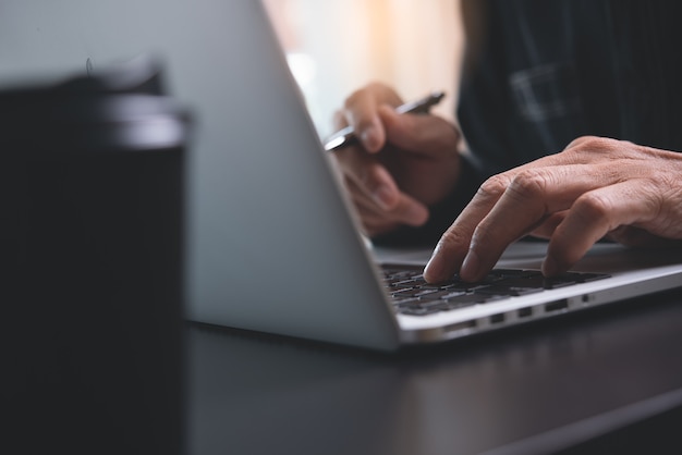 Close up of man hands typing on laptop computer on office table