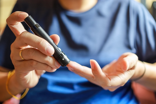 Close up of man hands using lancet on finger to check blood sugar level