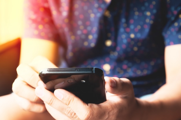 Photo close up of man hands using social media via smartphone.