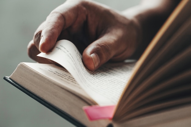 Chiuda sulle mani dell'uomo. giovane uomo che apre e che legge un libro,