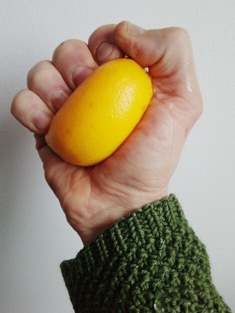 Close-up of man holding apple against white background