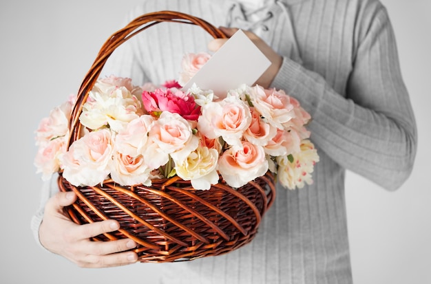 close up of man holding basket full of flowers and postcard.