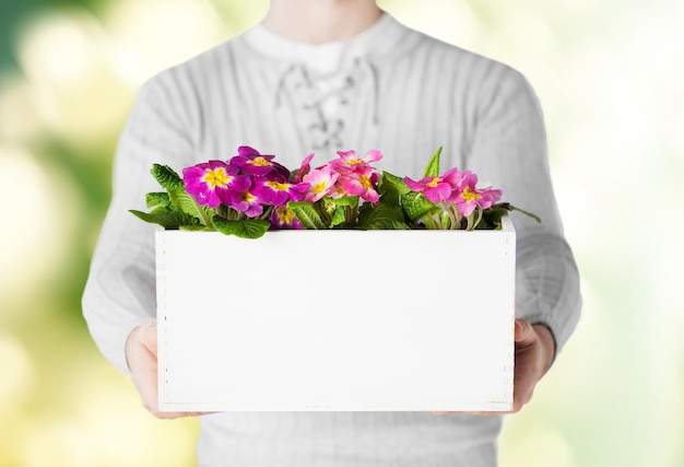 close up of man holding big pot with flowers