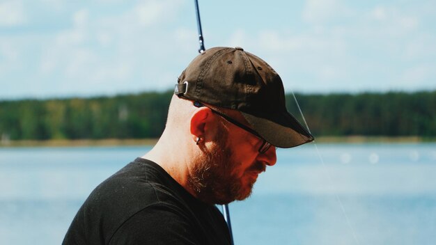 Foto close-up di un uomo con una canna da pesca in piedi vicino al lago