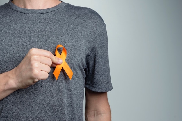 Close up on man holding orange ribbon on his shirt