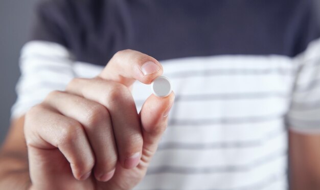 Close up of a man holding a pills.