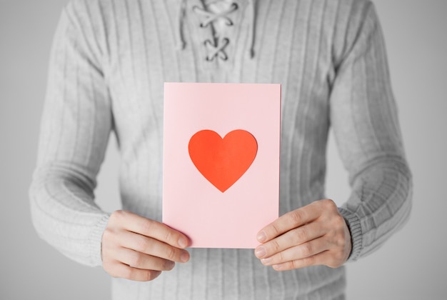 close up of man holding postcard with heart shape.