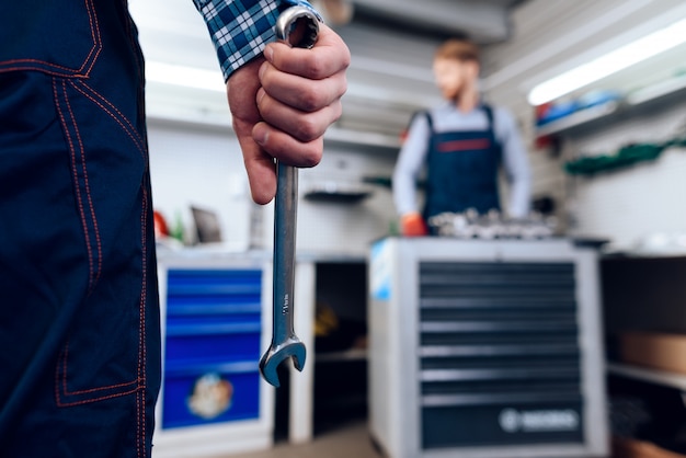 Close-up. Man Holds Wrench In Front Of Colleague.