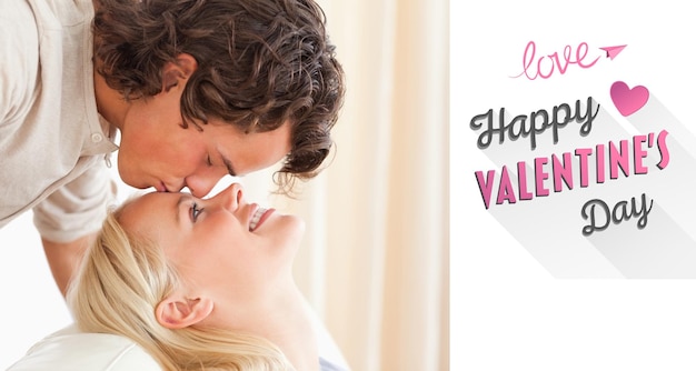 Close up of a man kissing his fiance on the forehead against cute valentines message