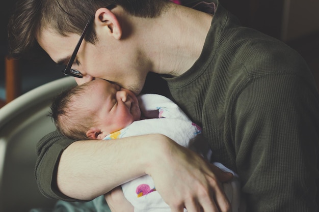 Close-up of man kissing newborn baby