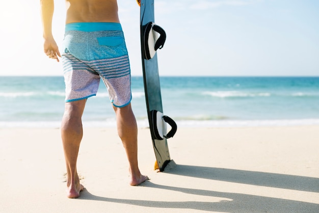 Close up of man legs and board in the beach.