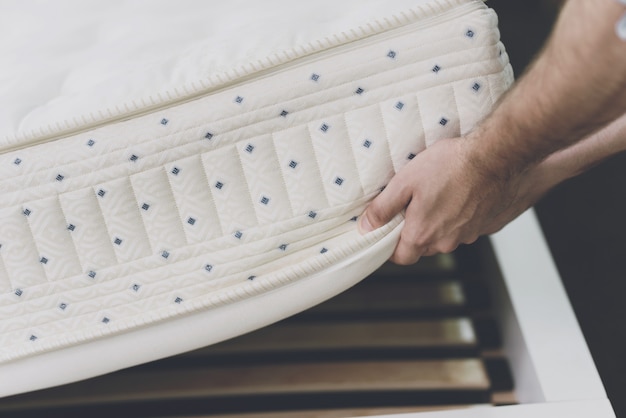 Close up Man lifted the mattress to look at the bed frame